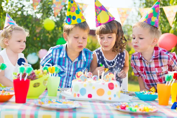Kids blowing candles on cake at birthday party