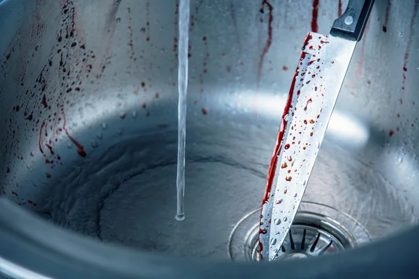 Cleaning bloody knife in kitchen sink