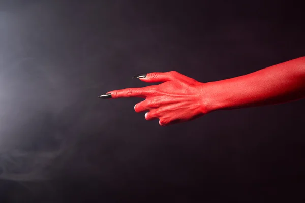 Red devil pointing hand, extreme body-art