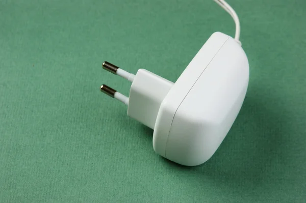 White electrical cable with plug on the green background