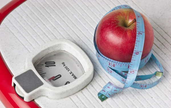 Apple and measuring tape on the floor scales