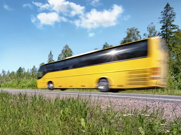 Yellow tourist bus speeding on rural highway, motion blur, with reflecting