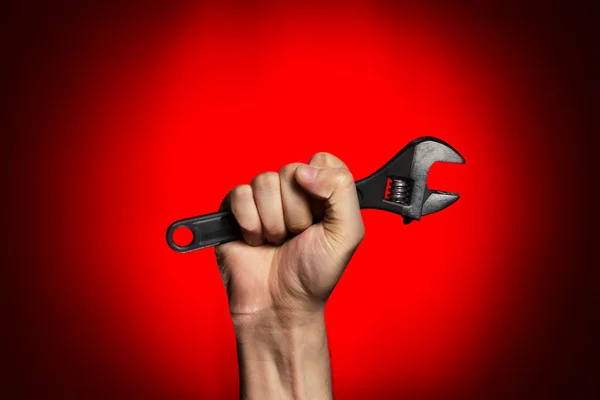 Man holding adjustable wrench over red