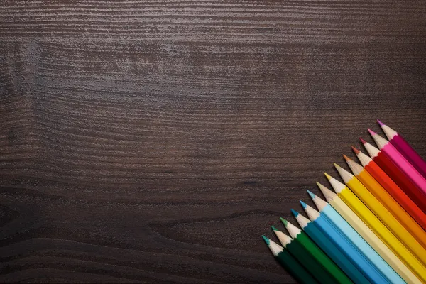 Colorful pencils over brown table background