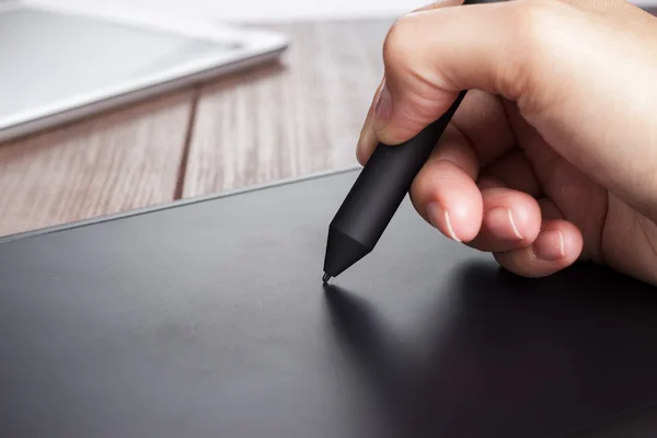 Hand of the designer with pen on tablet