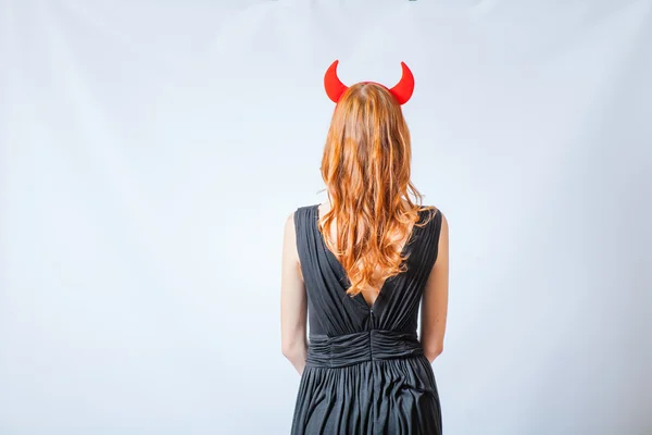 Backview of a red haired girl with horns like a devil