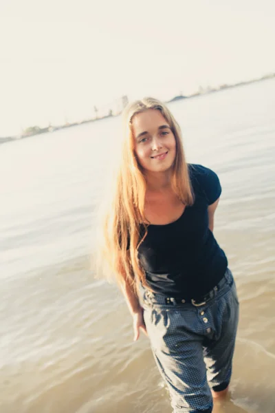 Cute blonde smiling against water of lake