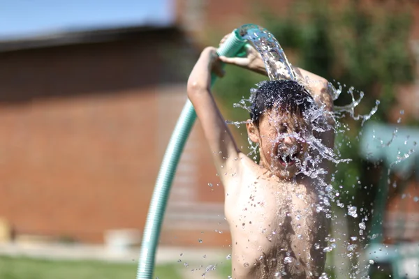 Boy with splash water in very hot summer day outdoors