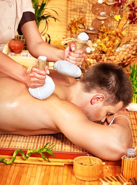 Man getting herbal ball massage treatments .