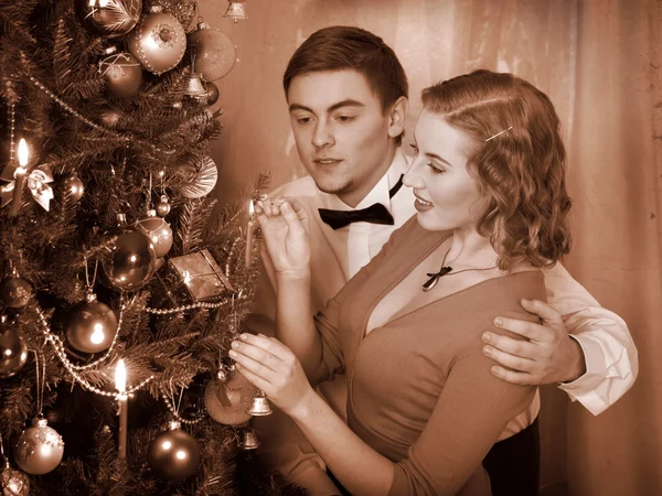 Couple ignites candles on Christmas tree.