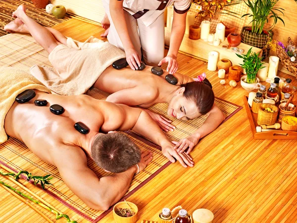 Woman and man getting stone therapy massage in spa.