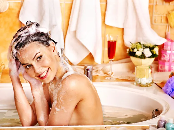 Woman washes her head at bathroom.