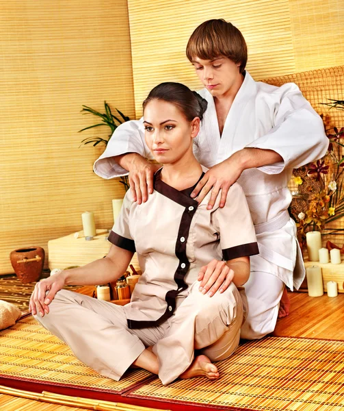 Male masseur doing massage woman in bamboo spa.