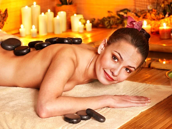 Woman getting stone therapy massage in bamboo spa