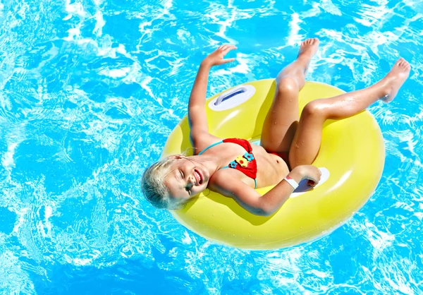 Child on inflatable in swimming pool.