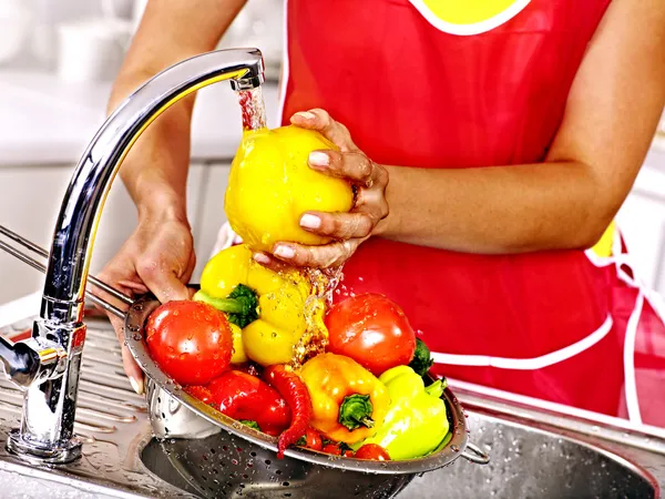 Woman washing fruit at kitchen.