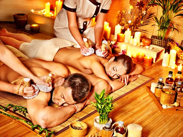 Man and woman getting herbal ball massage in spa.