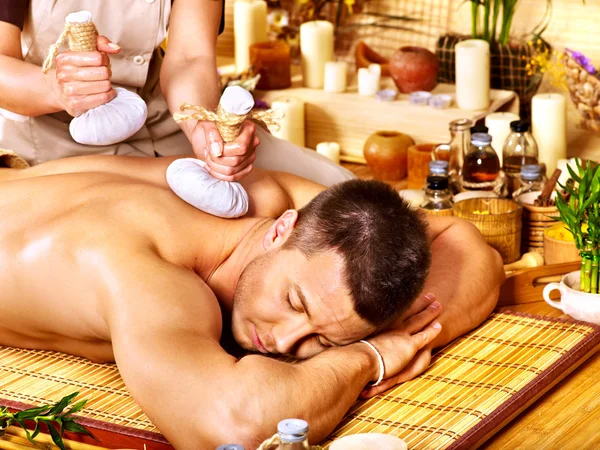 Man getting herbal ball massage treatments .