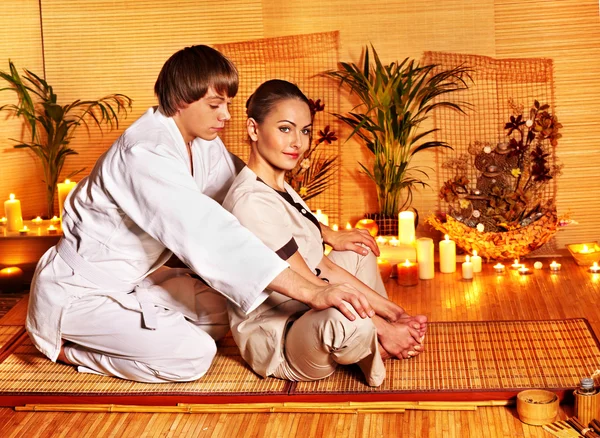 Male masseur doing massage woman in bamboo spa.