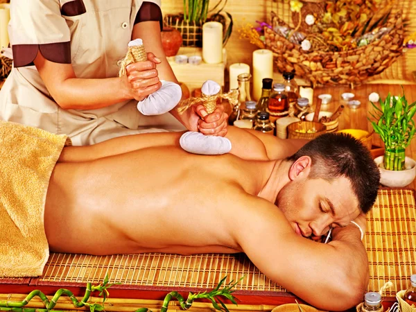 Man getting herbal ball massage treatments .