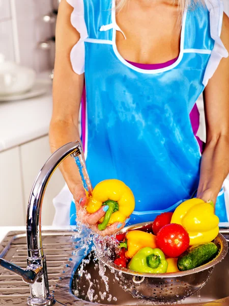 Woman washing fruit at kitchen.