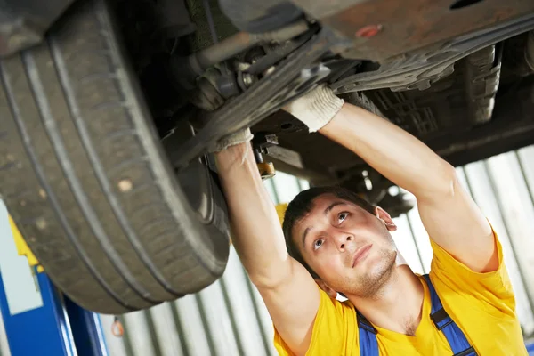 Auto mechanic at car suspension repair work