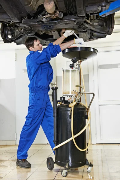 Car mechanic replacing oil from motor engine