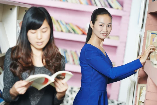 Young chinese student girl with book in library