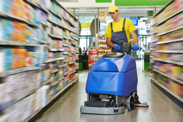 Worker cleaning store floor with machine
