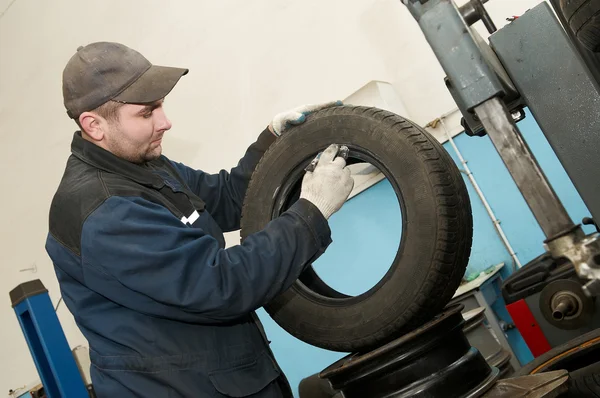 Repairman lubricating car tyre