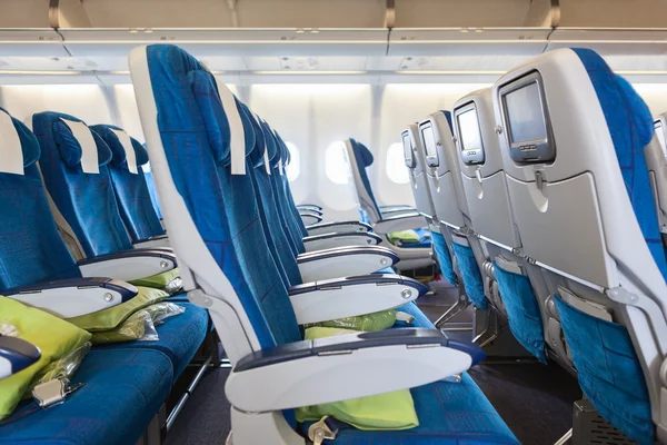 Comfortable seats in cabin of huge aircraft with screens in chairs back