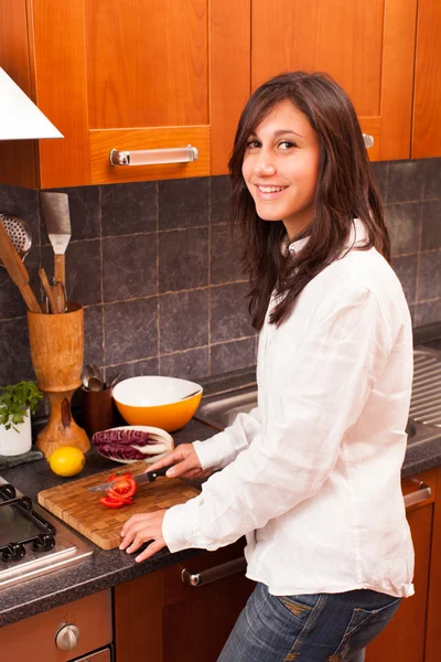 Young Woman Cutting Tomato in the Kitchen