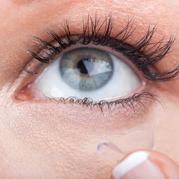 Woman eye with contact lens applying