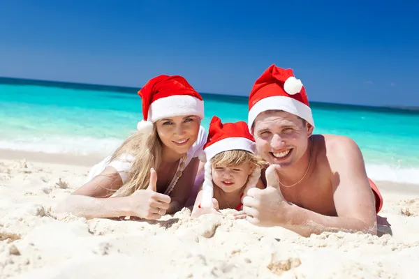 Happy family on beach in Santa hats, celebration christmas