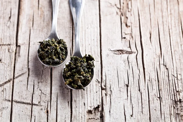 Two spoons of dried green tea leaves