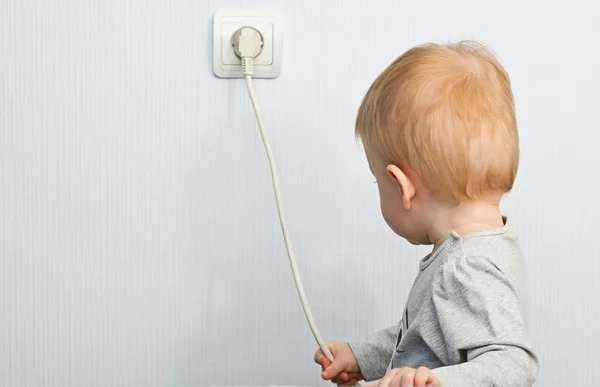 The one-year-old child pulls for an electric wire