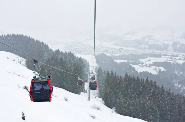 Ski lift cabins against of Kirhberg, Austria. Snowfall