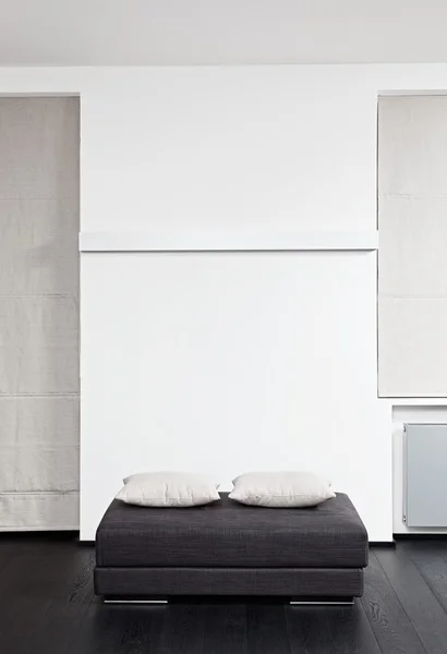 Dark gray padded stool with white pillow, detail of modern sitting room interior in black and white — Stock Photo #12445169