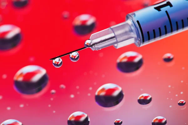 Syringe needle with fluid drops on droplets water background, ma