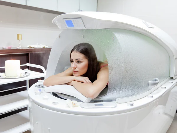 Young beautiful woman at steam SPA capsule