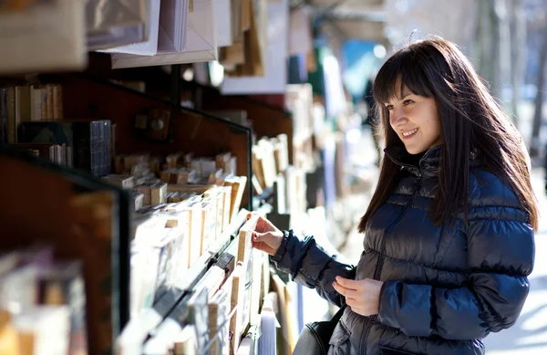 Beautiful woman in Paris selecting a book in an outdoor booksell