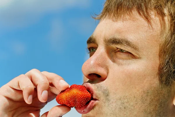 Man eating strawberry.