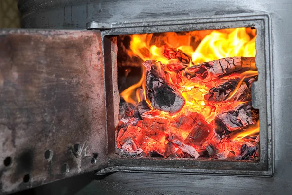 Old stove with open door and burning the wood