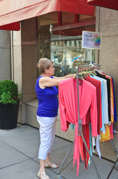 Woman chooses clothes on a hanger outside the shop on the street