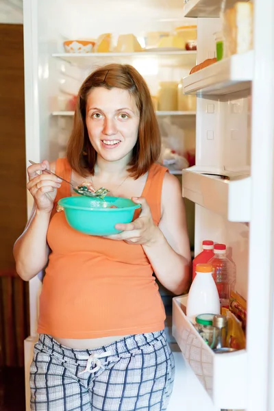 Pregnant woman eating from refrigerator