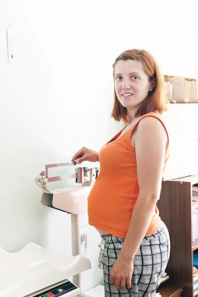 Pregnant woman weighing on scales