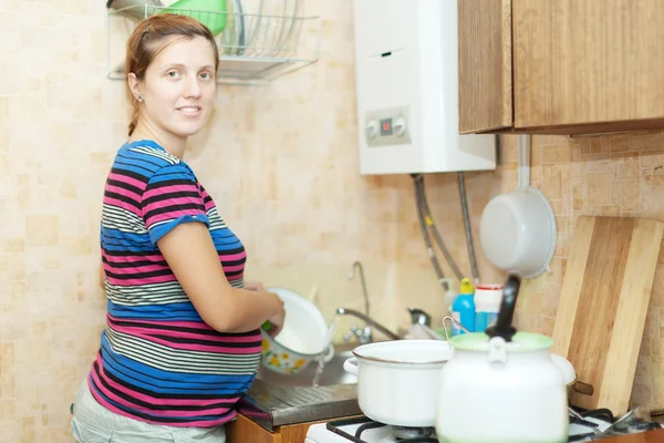 Pregnant woman washes dishes