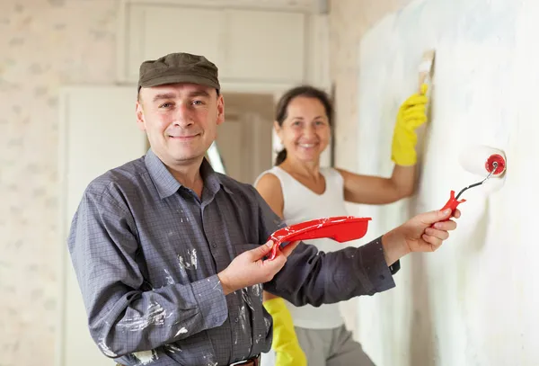 Happy man and woman paints wall at apartment