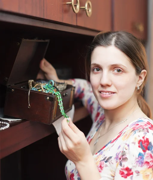 Woman looks jewelry in treasure chest