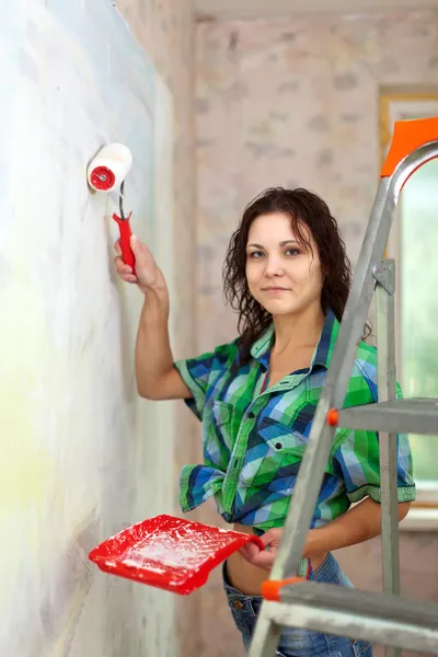Woman paints wall with roller